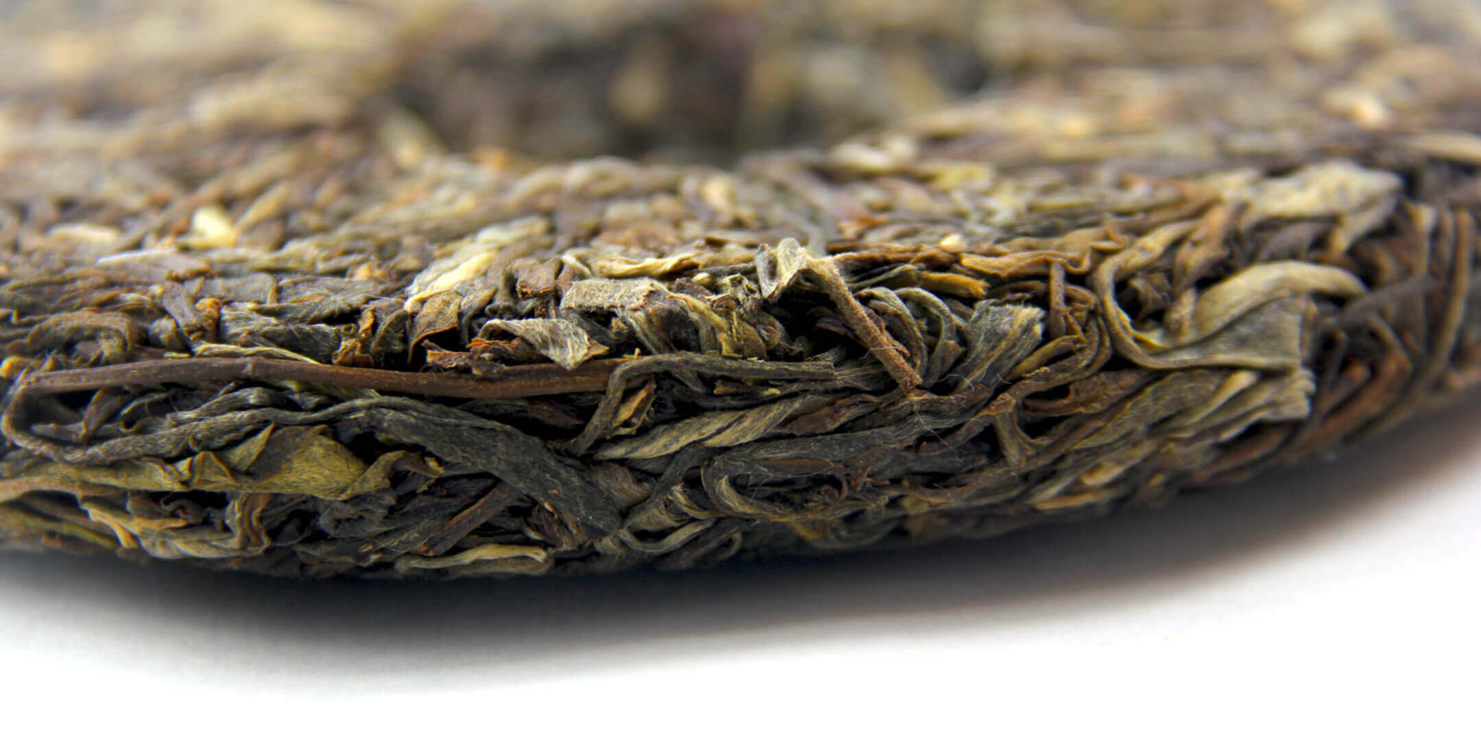 Finest collection of Chinese Puerh teas, sourced directly from Yunnan. Picture of the side of a Sheng Puerh tea cake.