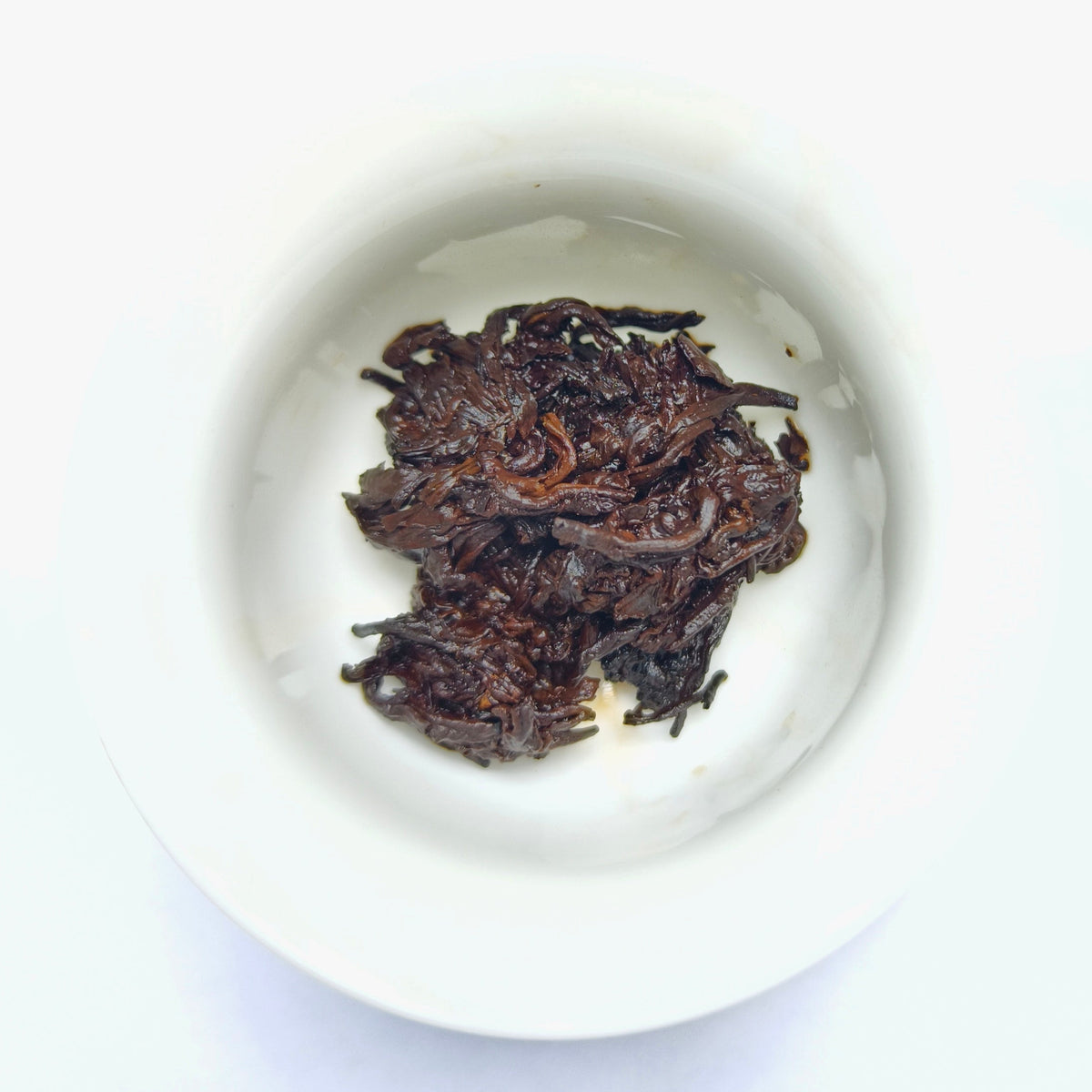 Lao Cha Tou Ripe Puerh tea wet tea leaf having being infused in a white dehua porcelain gaiwan.