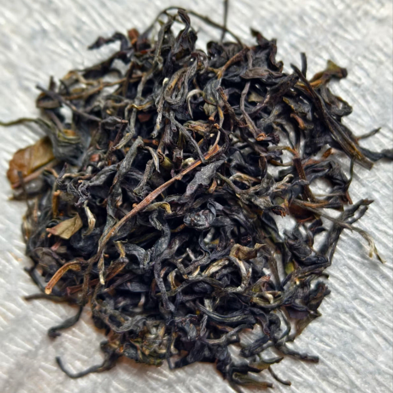 Youyun Old Bush Tie Guan Yin (Miben Series) dry leaf appearance with dark green and brown hues.