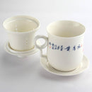 Lotus design tea mug set. Lidded tea mug with saucer. View of the backside of the mug showing the Chinese characters.